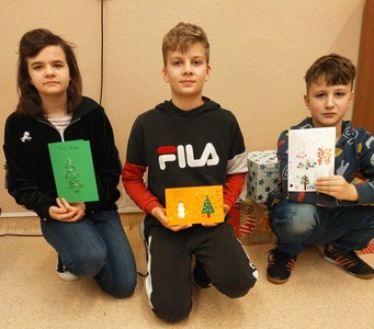 Uczniowie z wykonanymi kartkami świątecznymi. 