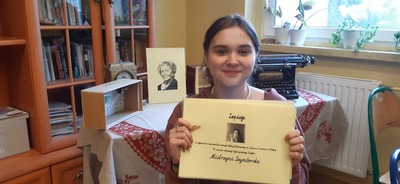 Uczennica trzymająca plakat dotyczący Wisławy Szymborskiej. 