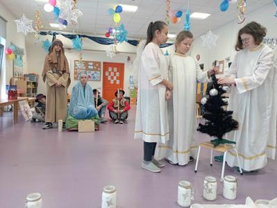 troje dzieci przebranych za aniołki ubiera choinkę