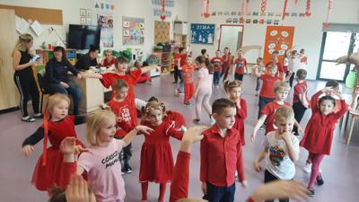 bal walentynkowy , dzieci ubrane na kolor czerwony bawią się w zabawy i tańczą na dużej sali