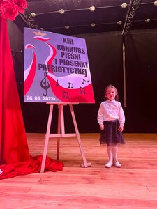 dziewczynka na scenie obok dużej tablicy