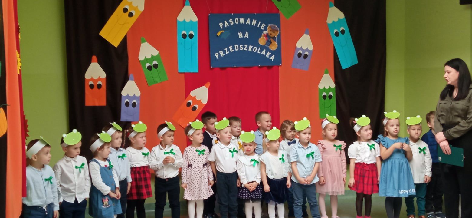 Grupa dzieci i pani dyrektor podczas uroczystości pasowania na przedszkolaka.