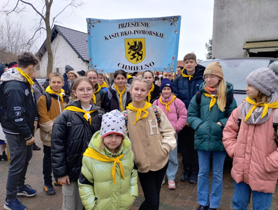 Grupa uczniów trzyma baner z napisem Zrzeszenie Kaszubsko - Pomorskie Chmielno. Dzieci na szyi maja zawiązane żółte chustki. 
