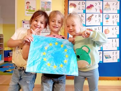 Uczennice oddziału przedszkolnego prezentujące flagę Unii Europejskiej.
