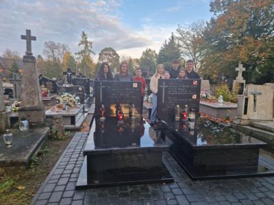 Nauczyciele z uczniami stojący wśród grobów.