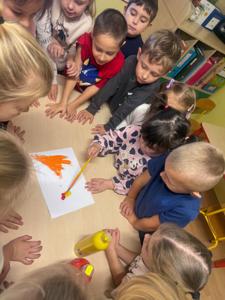 Dzieci mieszają farby, chcąc uzyskać kolor pomarańczowy.