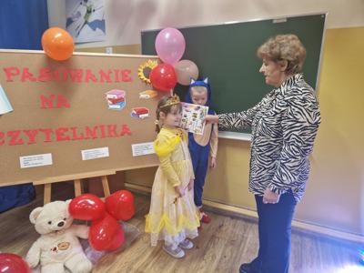 Pani Bibliotekarka pasuje na Czytelników uczniów klasy pierwszej.