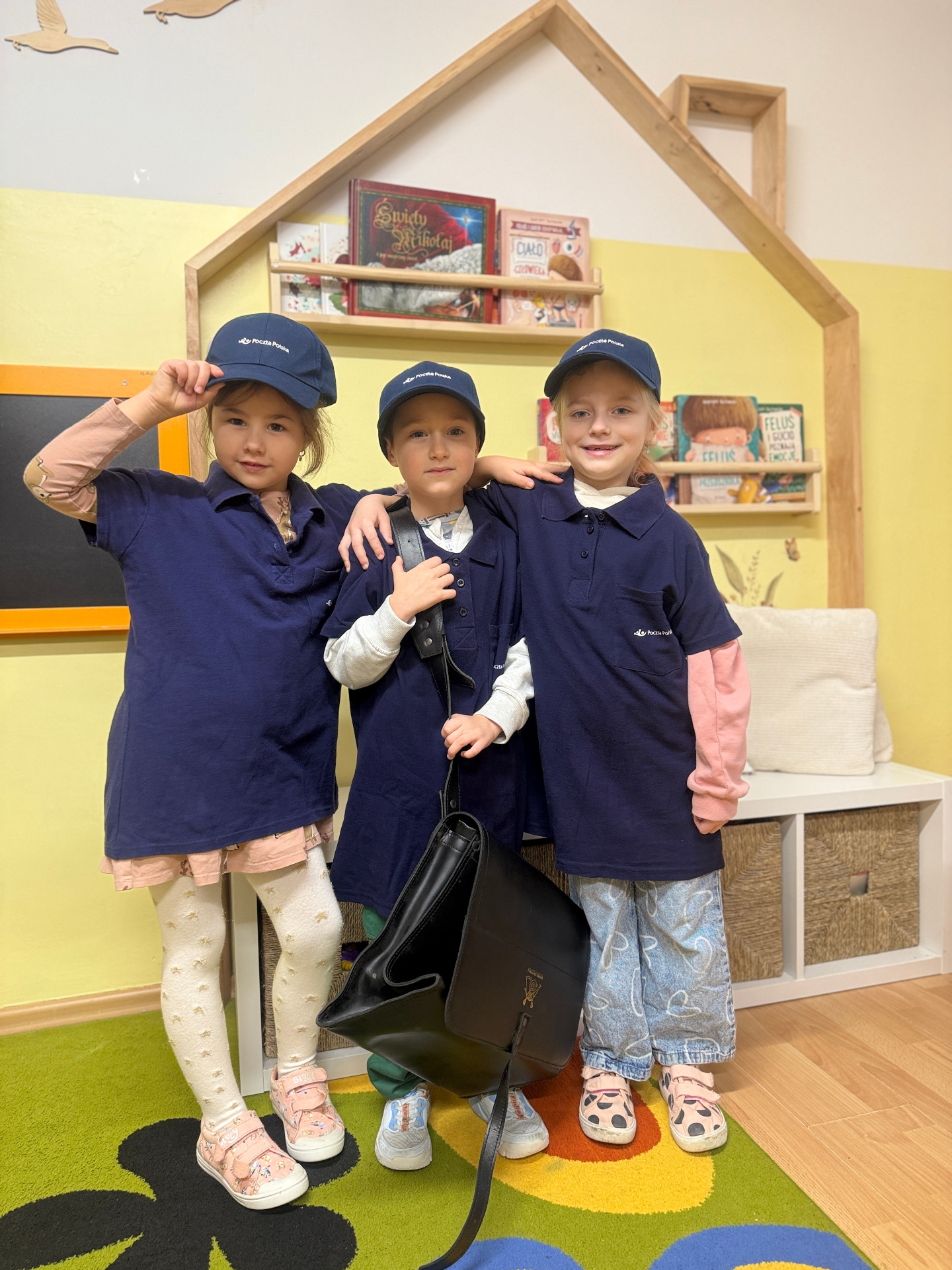 Przedszkolaki prezentują się w stroju listonosza.