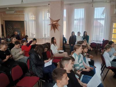 Publiczność uważnie słucha prezentacji przedstawianych przez uczniów.