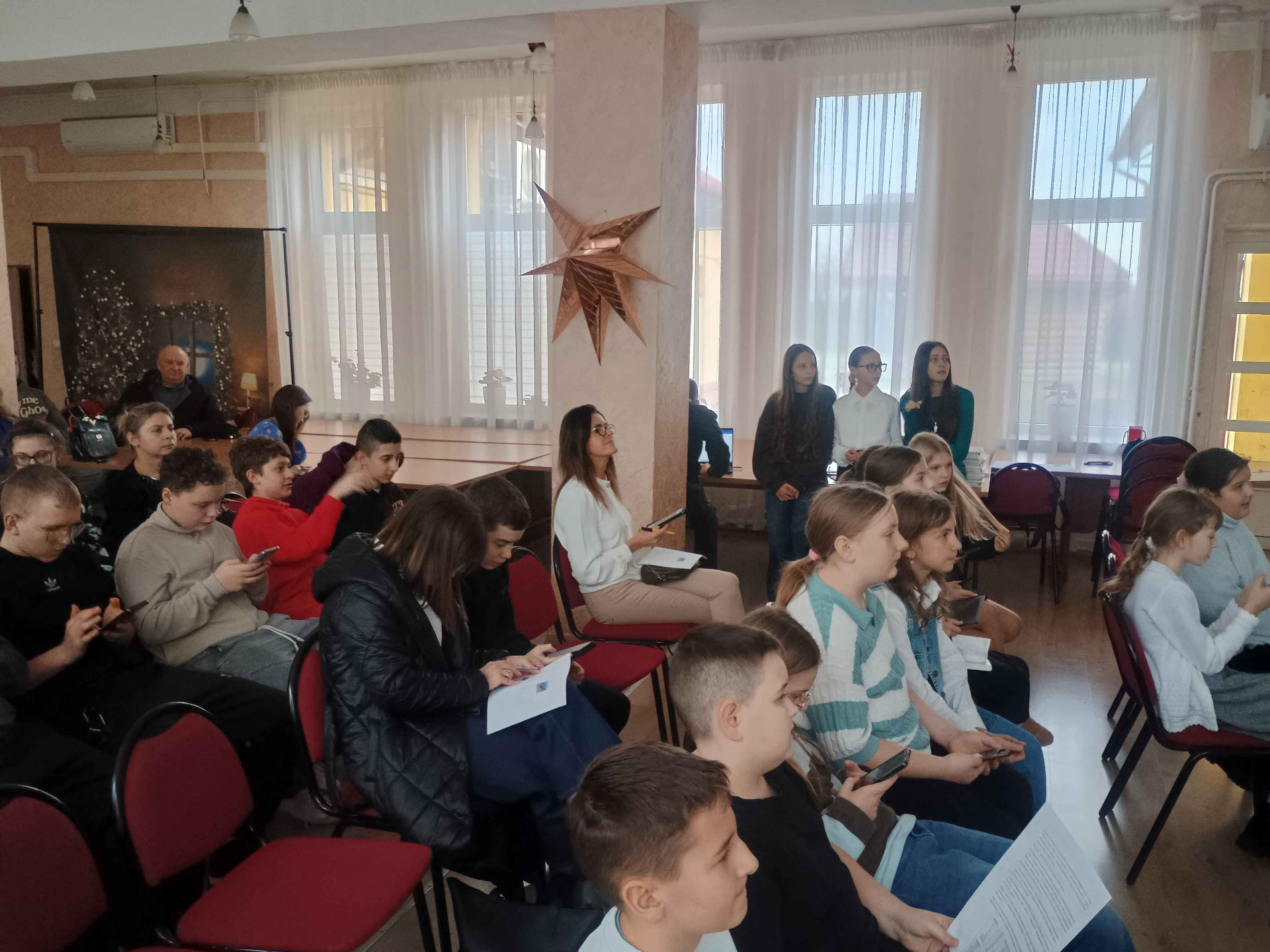 Publiczność uważnie słucha prezentacji przedstawianych przez uczniów.