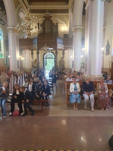 Grupa osób siedząca na ławkach w kościele. Msza święta w kościele rozpoczynająca nowy rok szkolny.
