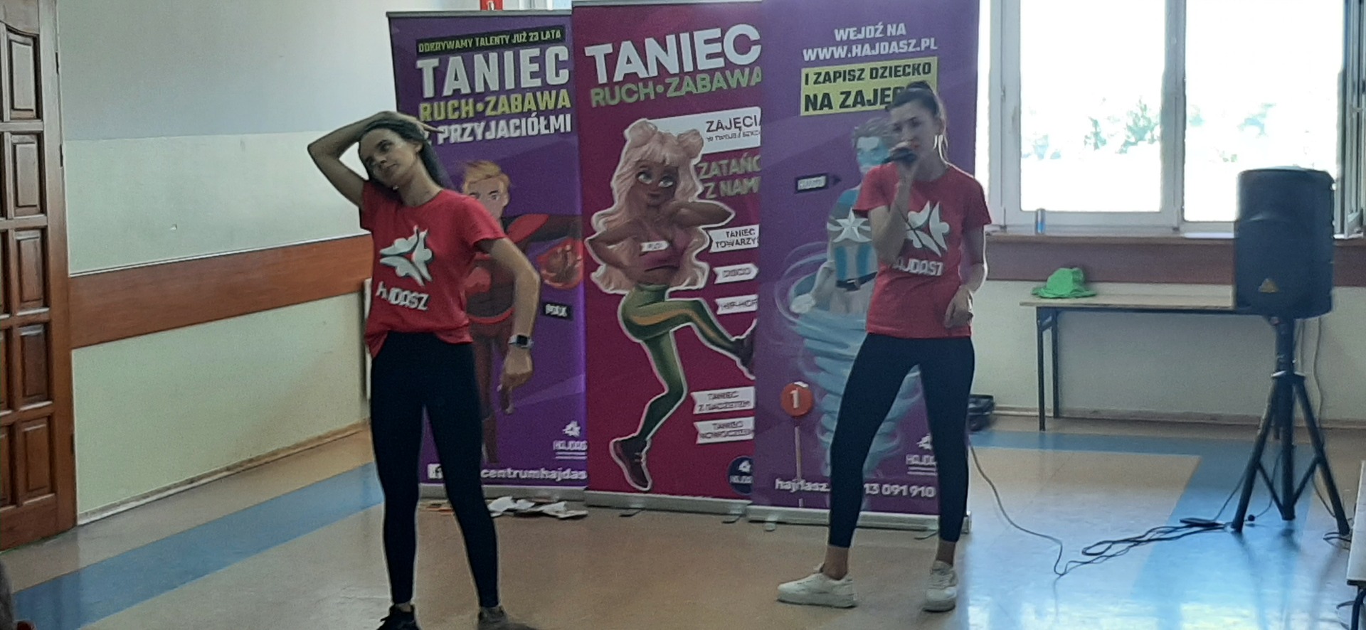 Dwie dziewczyny tańczą. W tle tablica z napisem taniec, ruch , zabawa.
