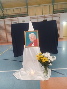 Portret Jana Pawła II obok bukiet kwiatów