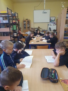 Grupa uczniów czytająca książki w bibliotece