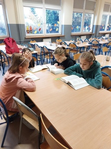 Uczniowie świetlicy szkolnej siedzą przy stole i czytają ulubione książki.