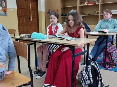 uczennica  przebrana za Roszpunkę siedzi w ławce i czyta swoją ulubioną bajkę.