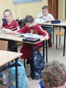 Uczeń siedzi w ławce w przebraniu Harrego Poterra, swojego ulubionego bohatera książkowego.