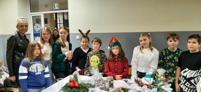 Dzieci wraz z wychowawcą stojące przy stoliku z bożonarodzeniowymi ozdobami.