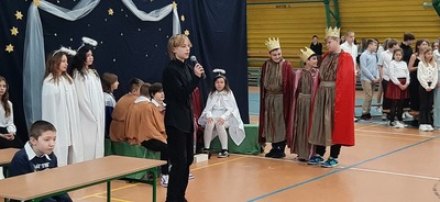 Trzej królowie, anioły i śpiewający uczeń na tle szopki bożonarodzeniowej.