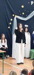 Śpiewająca uczennica na tle szopki bożonarodzeniowej.