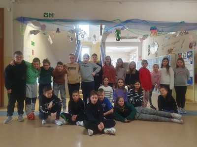 Grupa uczniów,w tle prace wykonane z materiałów z recyklingu