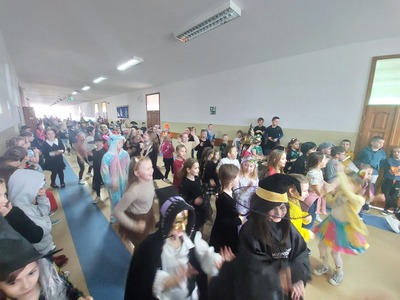 Duża grupa uczniów tańczy na korytarzu szkolnym