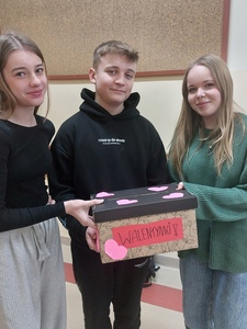 Korytarz szkolny - grupa uczniów trzyma w rękach pudełko na walentynki
