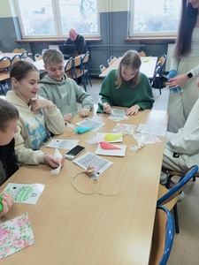 Uczniowie uczą się dekorować ciasteczka pod okiem nauczyciela