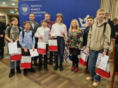 Uczniowie naszej szkoły, w ręku trzymają dyplomy oraz nagrody rzeczowe. Obok pani Barbara Kiraga oraz Naczelnik Oddziałowego Biura Edukacji IPN w Łodzi Arturem Ossowskim.