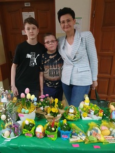 Dwóch chłopców z wychowawczynią przy stoliku z ozdobami świątecznymi