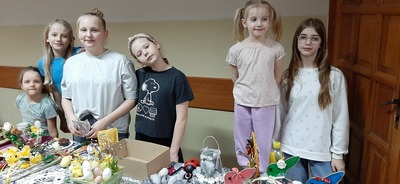 Uczniowie stojący przy stoliku z wielkanocnymi ozdobami.