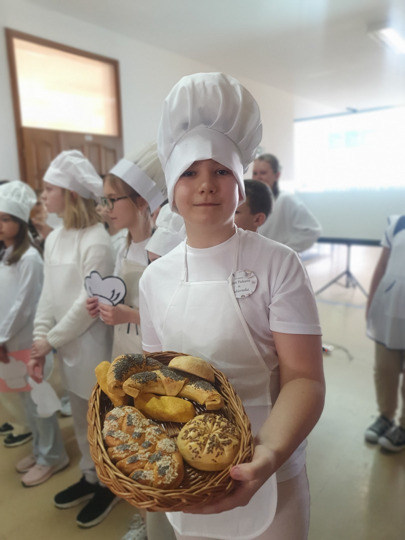Uczniowie w strojach piekarzy i cukierników częstują wypiekami