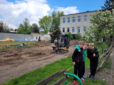 trzech uczniów na tle placu bodowy nowych zestawów do ćwiczeń
