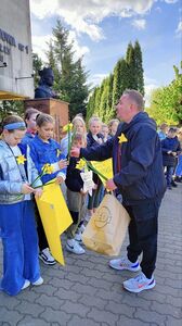 Pan Robert Kobylarczyk rozdaje żonkile przed szkołą aby uczniowie w trakcie marszu wręczyli je mieszkańcom Tuszyna.