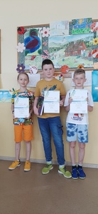 Trzej chłopcy trzymają dyplomy