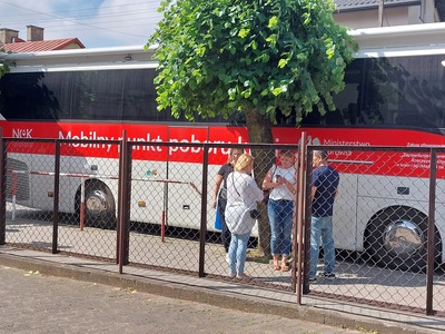 Grupa osób stojąca przed ambulansem do mobilnego poboru krwi