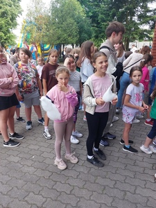 Grupa uczniów stojących w kolejce. Na przodzie dwie uczennice jedzące watę cukrową