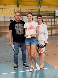 Hala sportowa. Na środku stoi uczennica z kl 7b, trzymając dyplom, wychowawca  oraz dyrekcja szkoły..