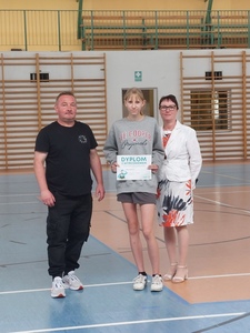Hala sportowa. Na środku stoi uczennica z kl 7c, trzymając dyplom, nauczyciel  oraz dyrekcja szkoły..