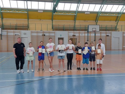 Hala sportowa. Grupa uczniów z klasy 4a stoi w szeregu, trzymając dyplomy. Obok nich stoi wychowawca i dyrekcja szkoły..