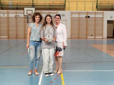 Hala sportowa. Na środku stoi uczennica z kl 7a, trzymając dyplom, wychowawczyni oraz dyrekcja szkoły.