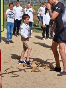 Teren zielony szkoły. Uczeń z klasy 2b otrzymuje nagrodę - bluzę sportową za wzorowo wykonane "pompki" na podpórkach.
