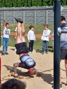 Teren zielony szkoły. Sztuczki akrobatyczne na podpórkach wykonane przez trenera Street Workoutu.