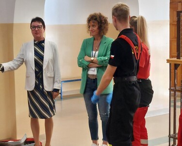 Pani dyrektor na holu szkoły w obecności  nauczyciela, strażaka o raz ratownika medycznego.