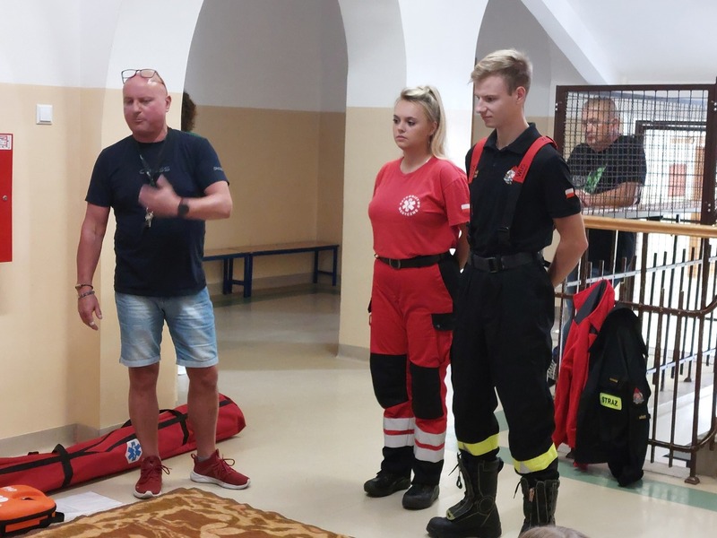 Nauczyciel , strażak oraz ratownik medyczny na holu szkoły.
