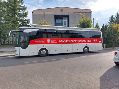 Mobilny punkt poboru krwi stojący przed budynkiem szkoły