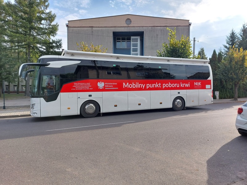 Mobilny punkt poboru krwi stojący przed budynkiem szkoły