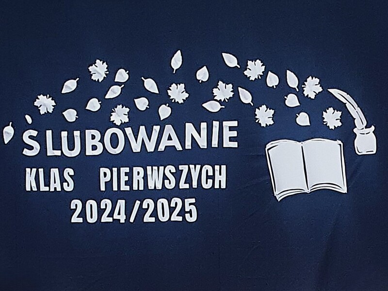 Dekoracja z napisem Ślubowanie Klas Pierwszych 2024/2025. Z boku napisu otwarta książka, kałamarz i pióro
