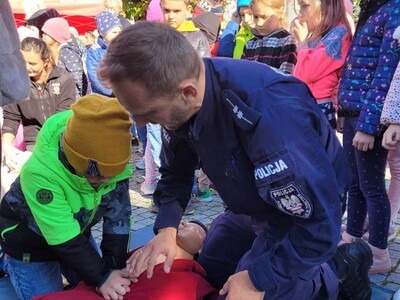 Uczeń pod nadzorem strażaka z OSP w Tuszynie wykonująca masaż serca na fantomie.