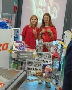 Uczennice przy wózku sklepowym wypełnionym darami.